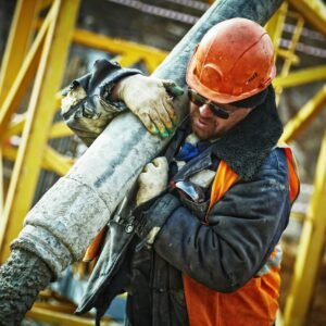 Construction worker in safety gear handling equipment on an active site.